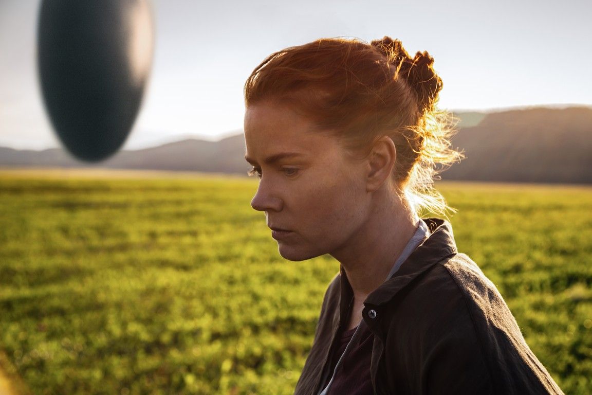 Woman in field gazes at alien ship.