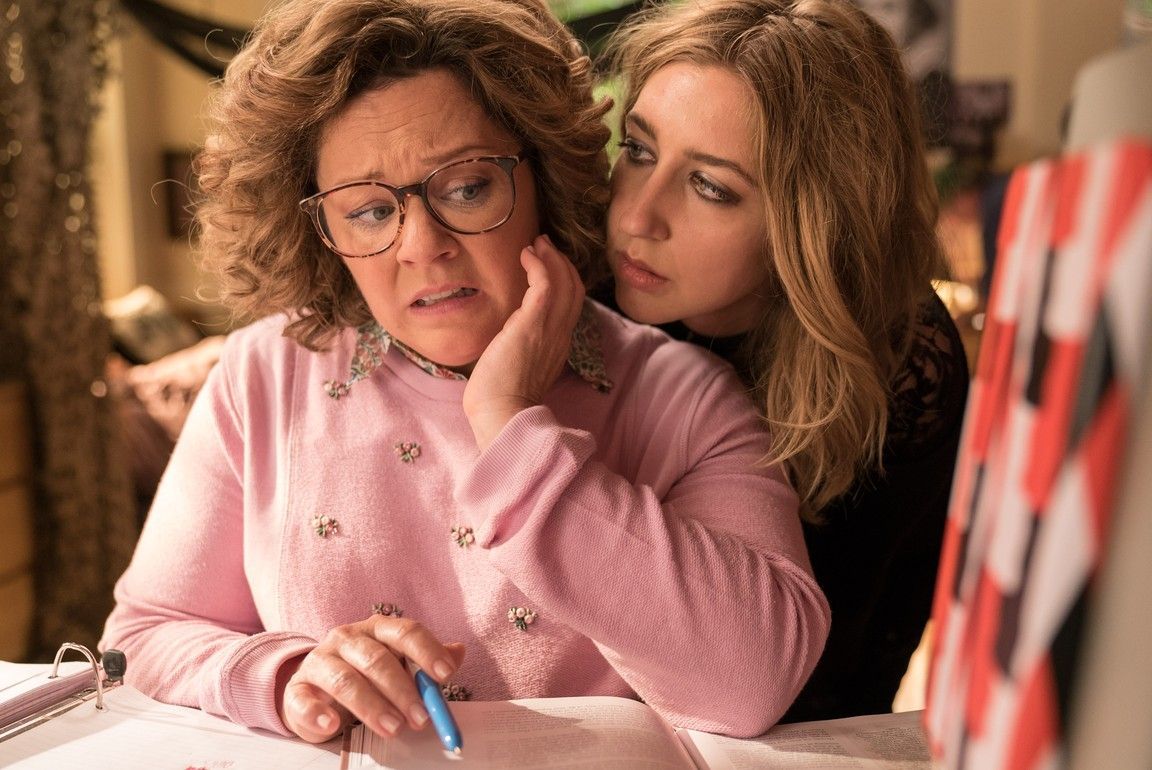 Melissa McCarthy and her daughter, a woman, look concerned, one with hand to cheek, in a home setting.
