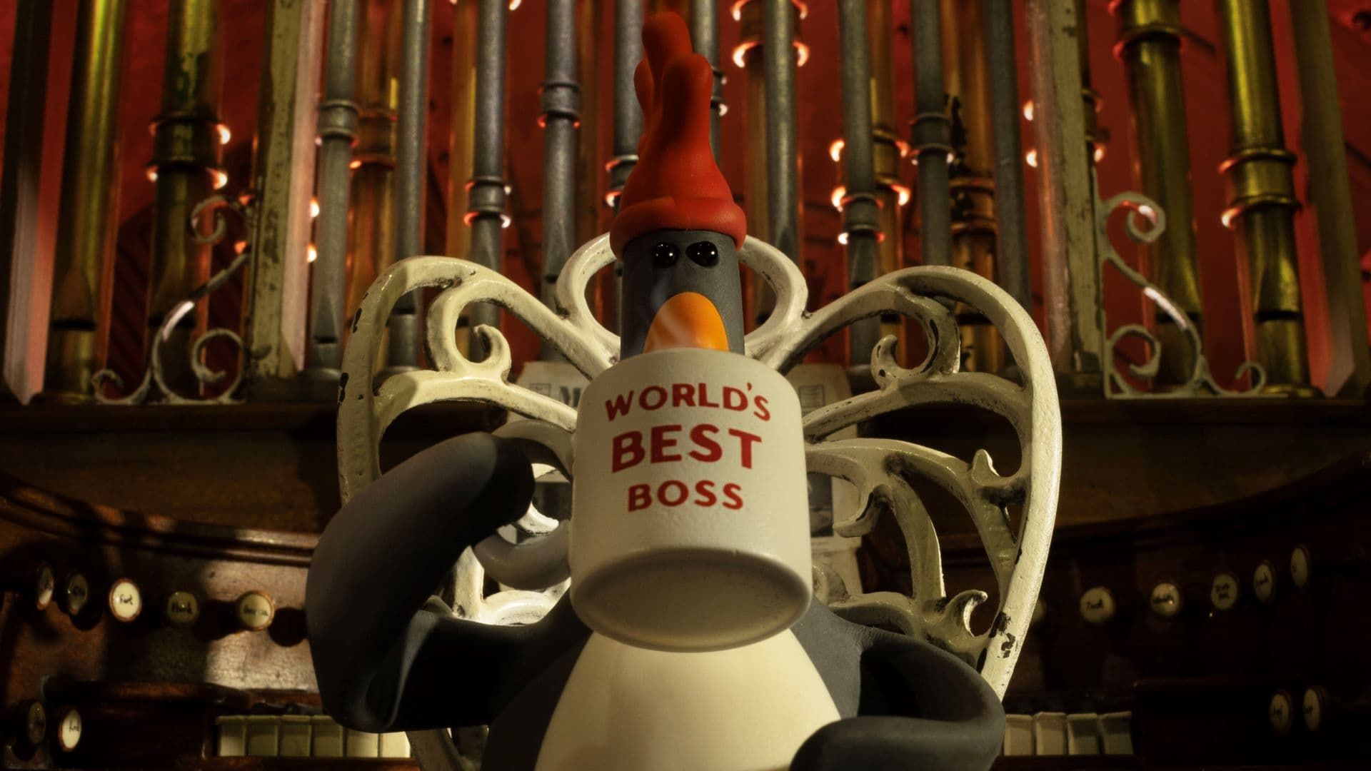 Penguin holding a mug labeled “World’s Best Boss” in front of organ pipes