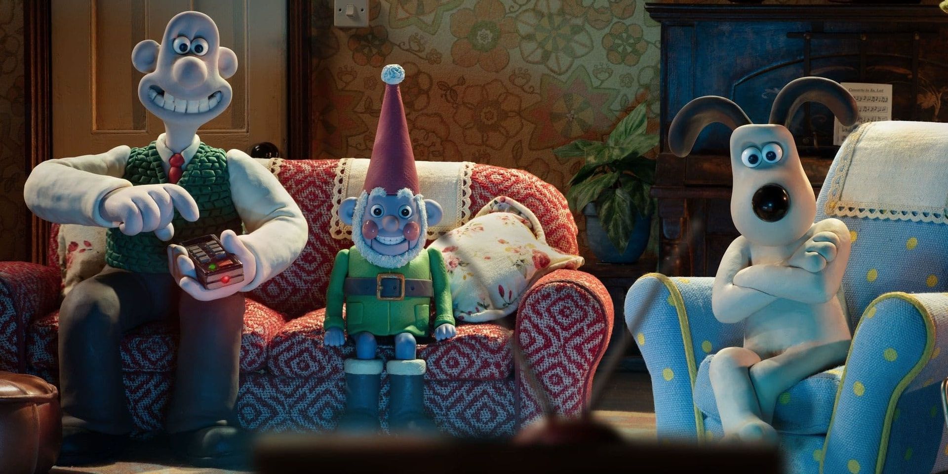 Wallace, Gromit, and Shaun the Sheep sit in a cozy living room, each on a patterned couch.