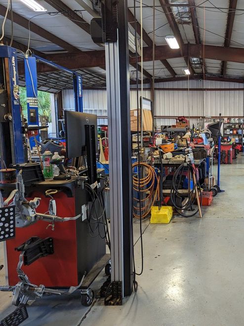 Inside a car repair shop, a wheel alignment machine is in the foreground | Dunedin Garage