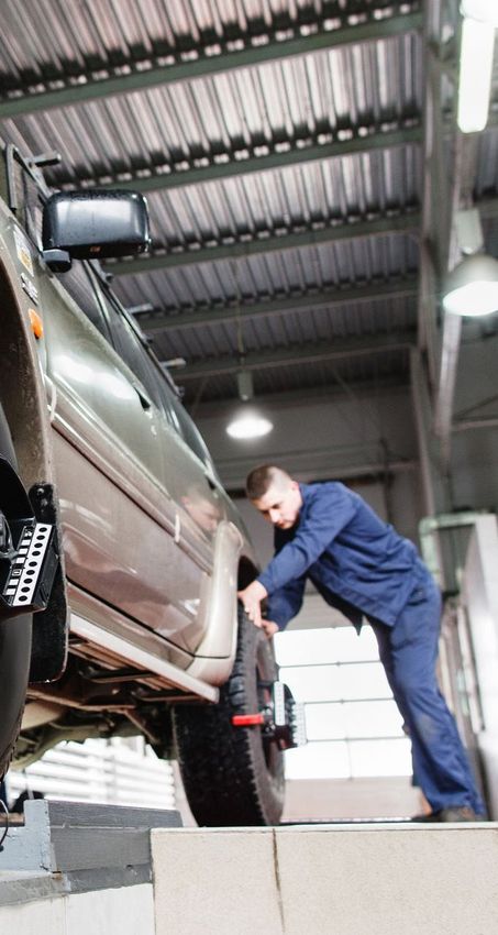 Mechanic in blue uniform working on the front wheel of a vehicle | Dunedin Garage