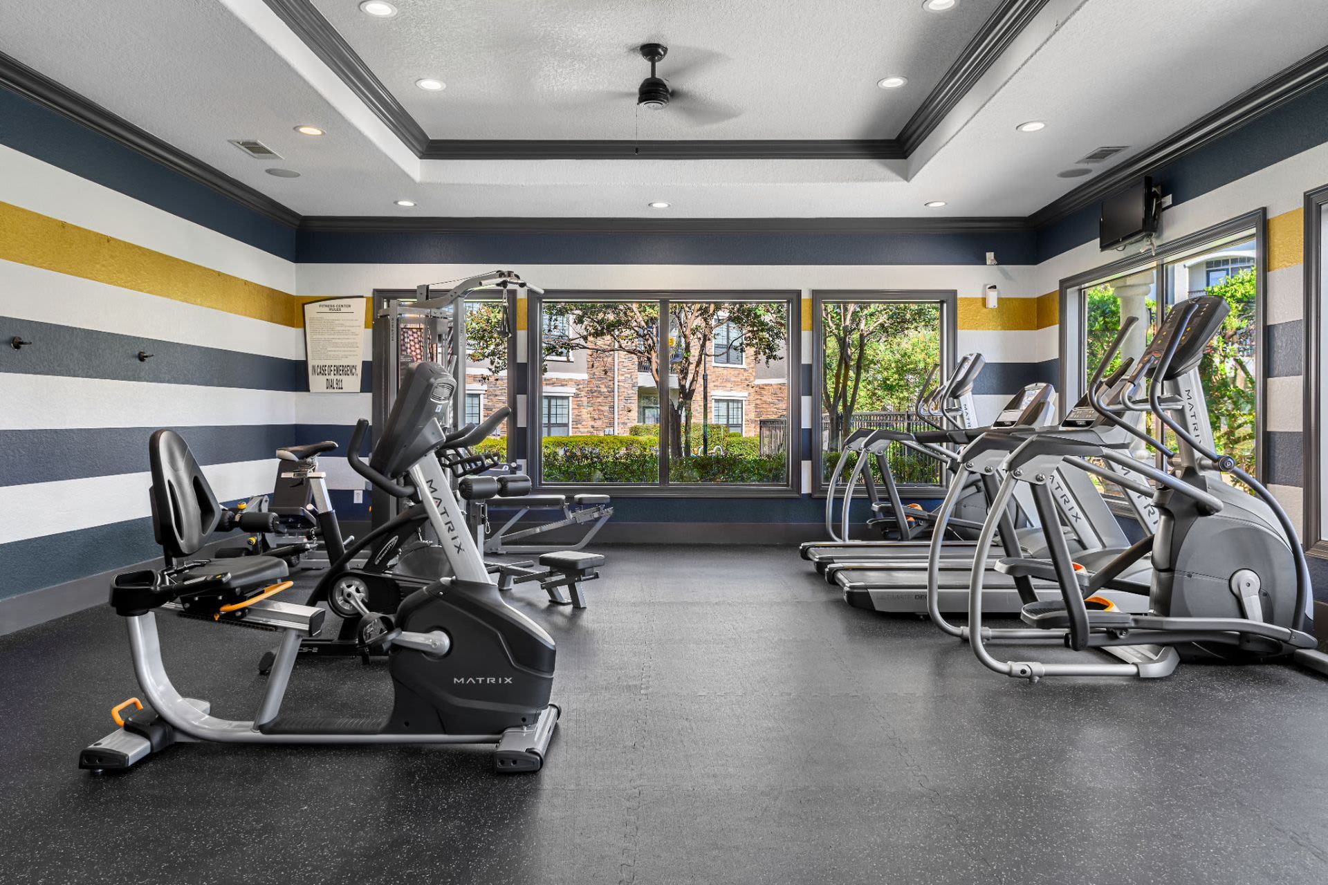 A gym with a lot of exercise equipment and a ceiling fan at Marquis Lakeline Station in Austin, TX.