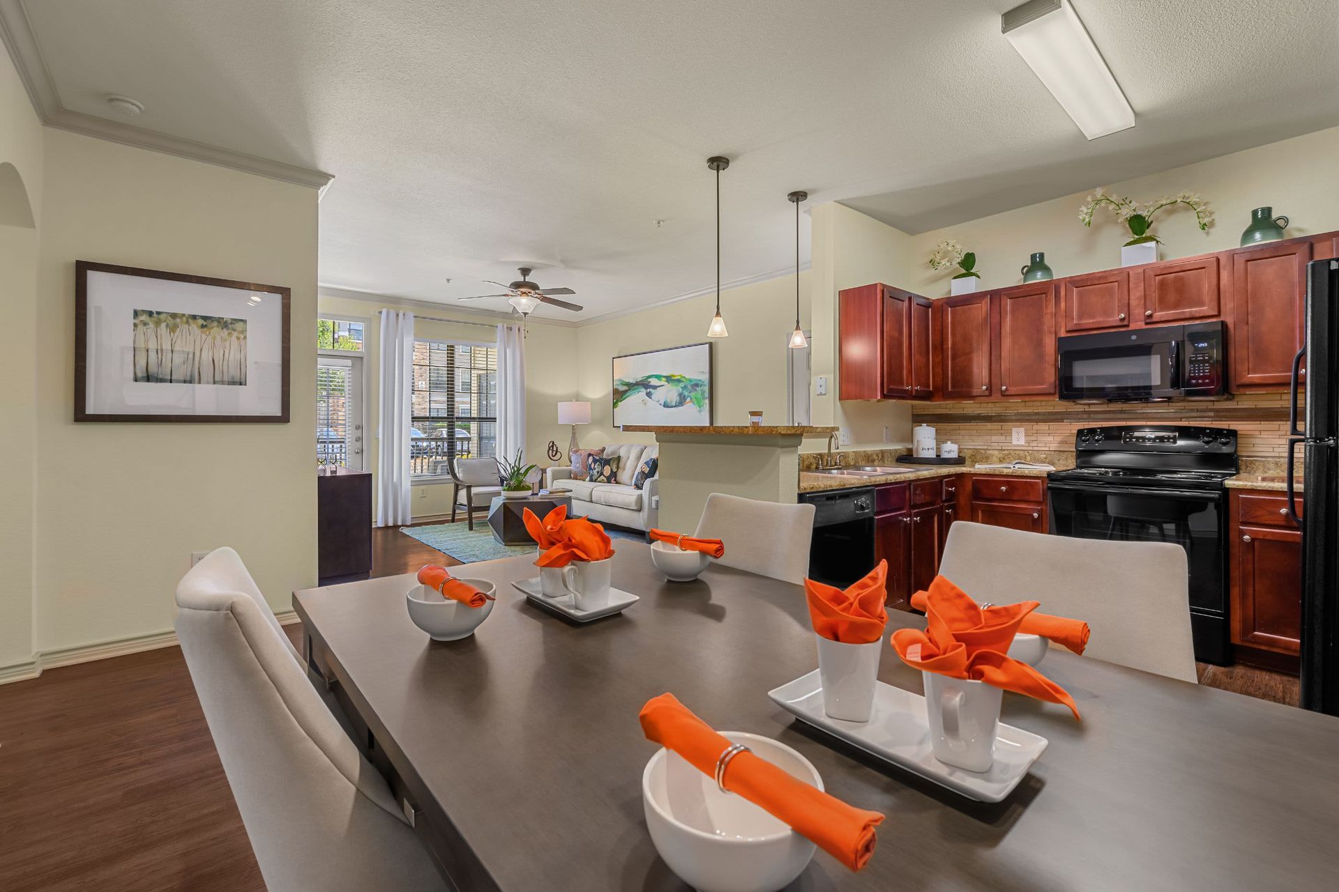 A dining room table with bowls and napkins on it and a kitchen in the background at Marquis Lakeline Station in Austin, TX.