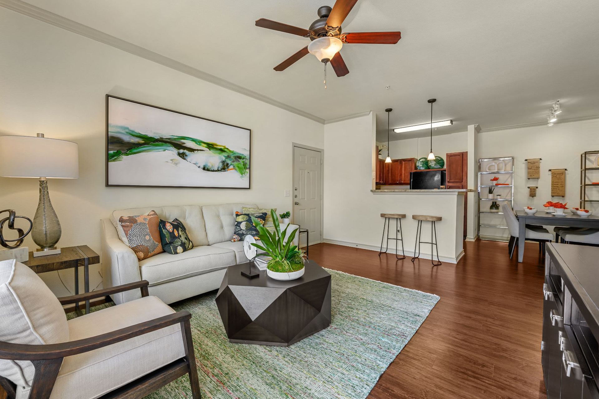 A living room with a couch, chair, coffee table, and ceiling fan at Marquis Lakeline Station in Austin, TX.