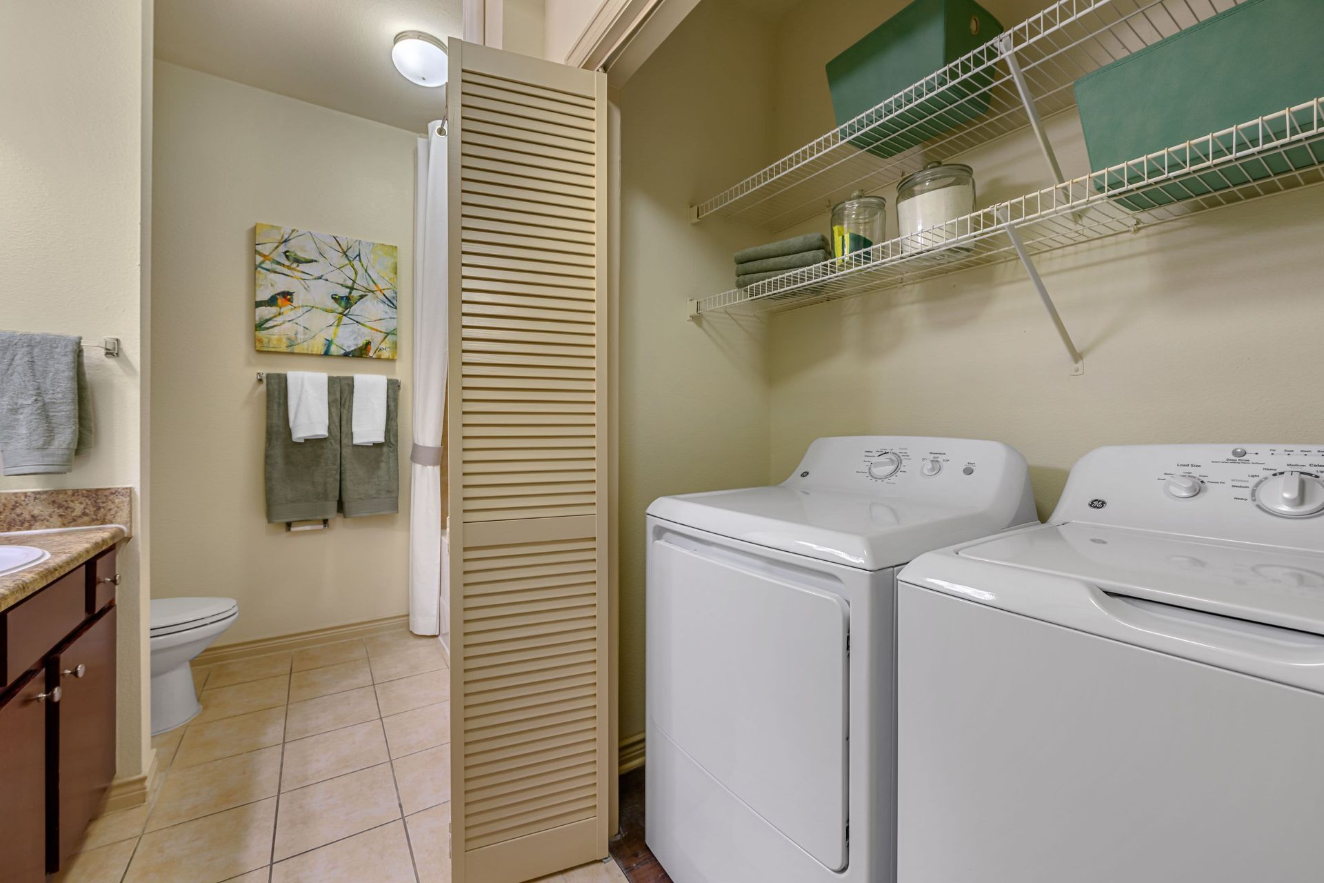 A laundry room with a washer and dryer next to a bathroom at Marquis Lakeline Station in Austin, TX.