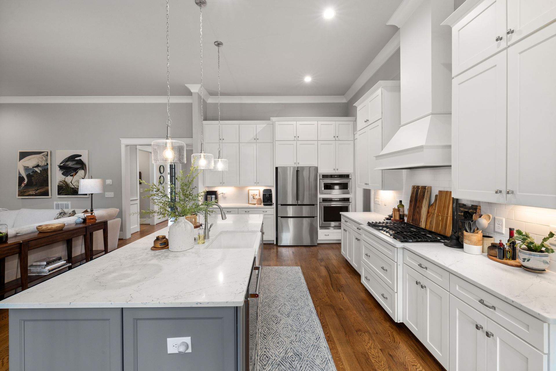 Modern kitchen with a marble island, wood stools, pendant lights, and large glass doors to a patio