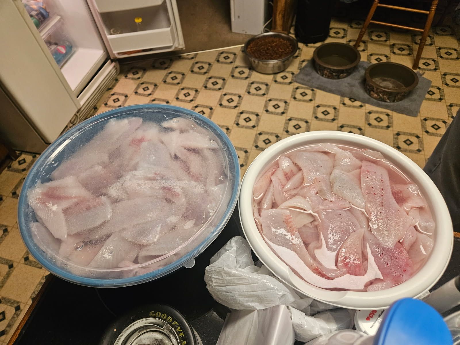Two tubs filled with ice and raw seafood on a kitchen floor
