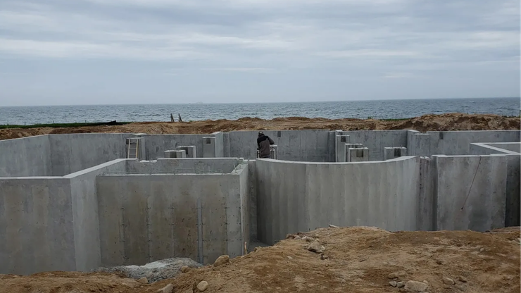 Concrete coastal barriers on a rocky shore with the sea in the background