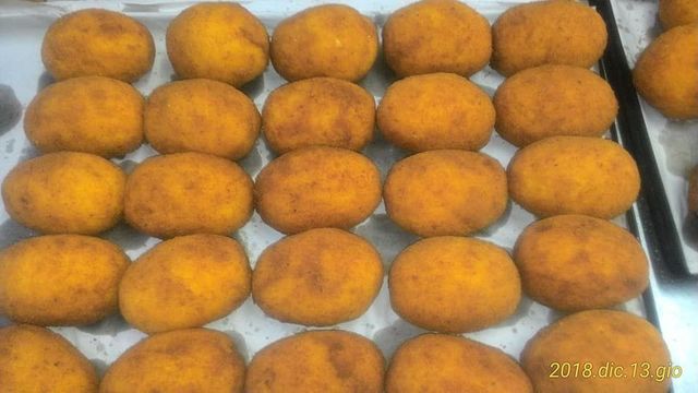 Un mucchio di palline di cibo fritto sono disposte una sopra l'altra su un tavolo.