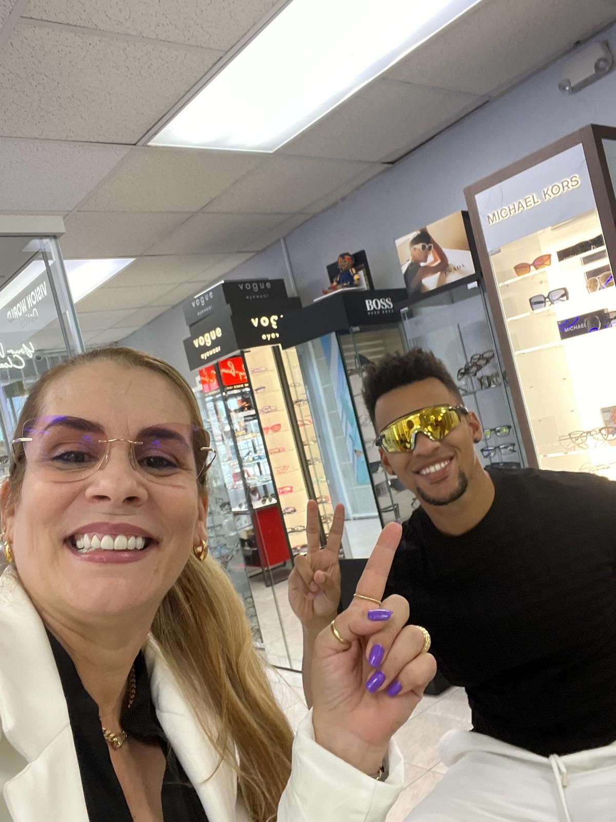 A man and a woman are posing for a picture in an optical shop.