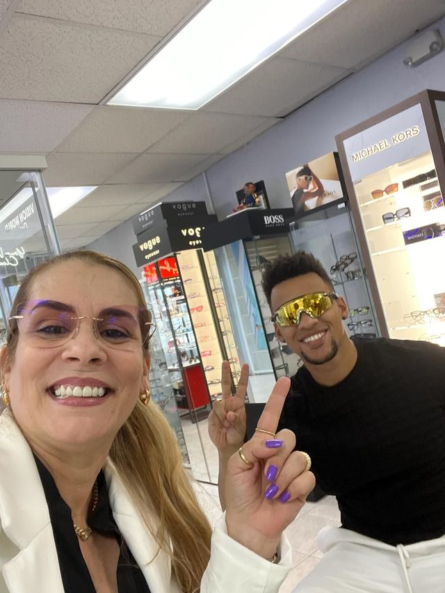 A man and a woman are posing for a picture in an optical shop.