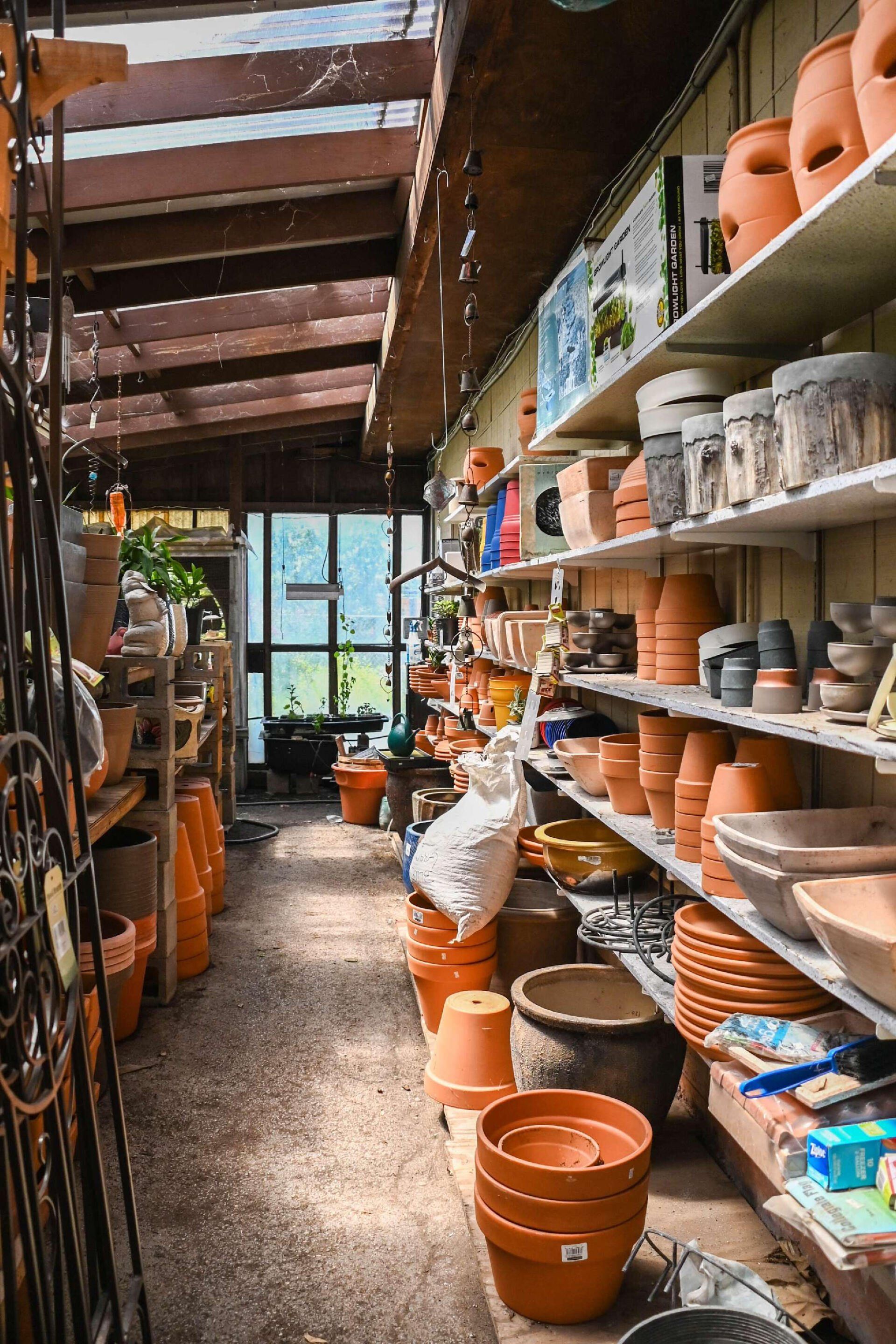 Pottery shop aisle with shelves of terracotta pots and ceramics in warm sunlight