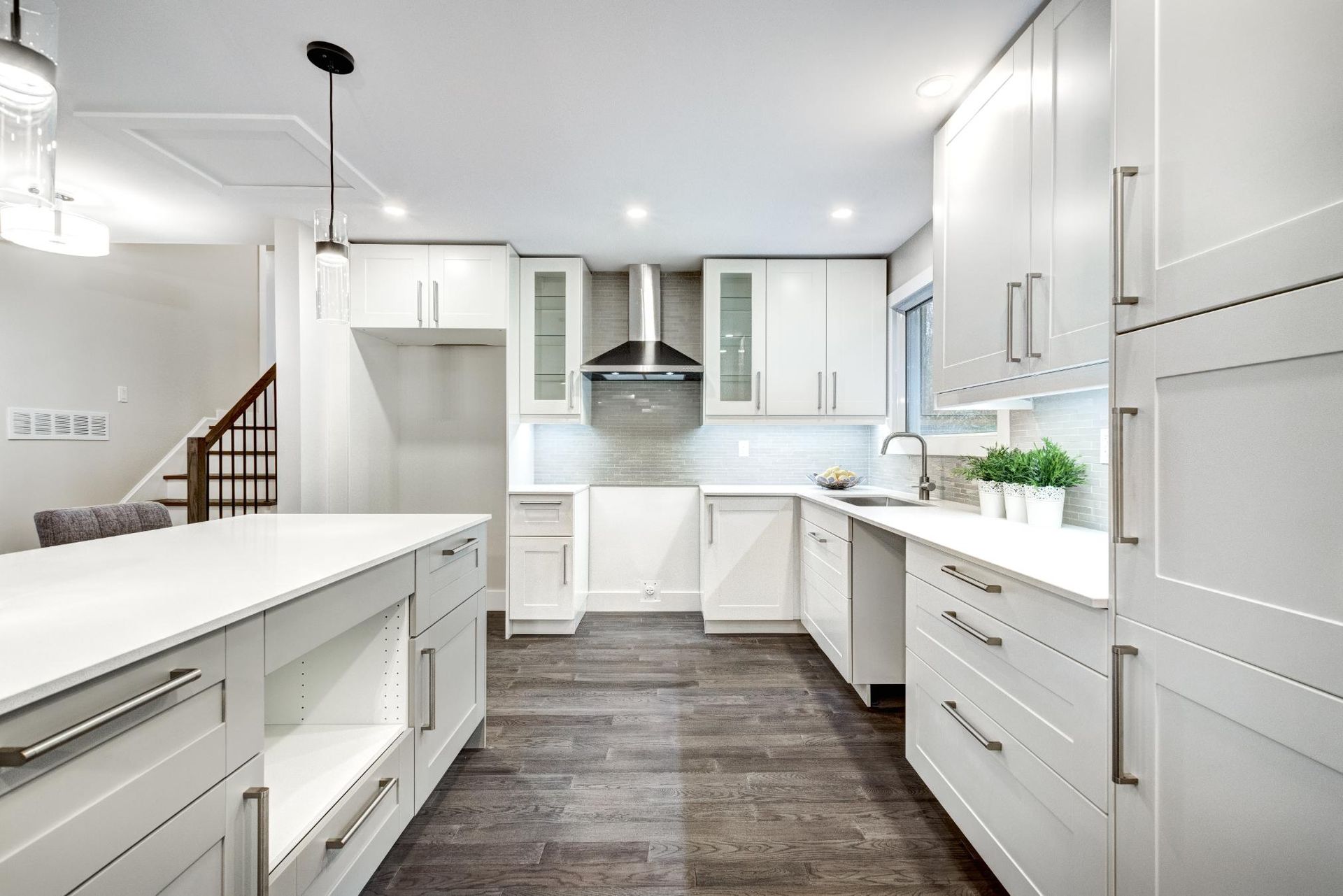 Bright white modern kitchen with island, stainless range hood, and dark wood floors