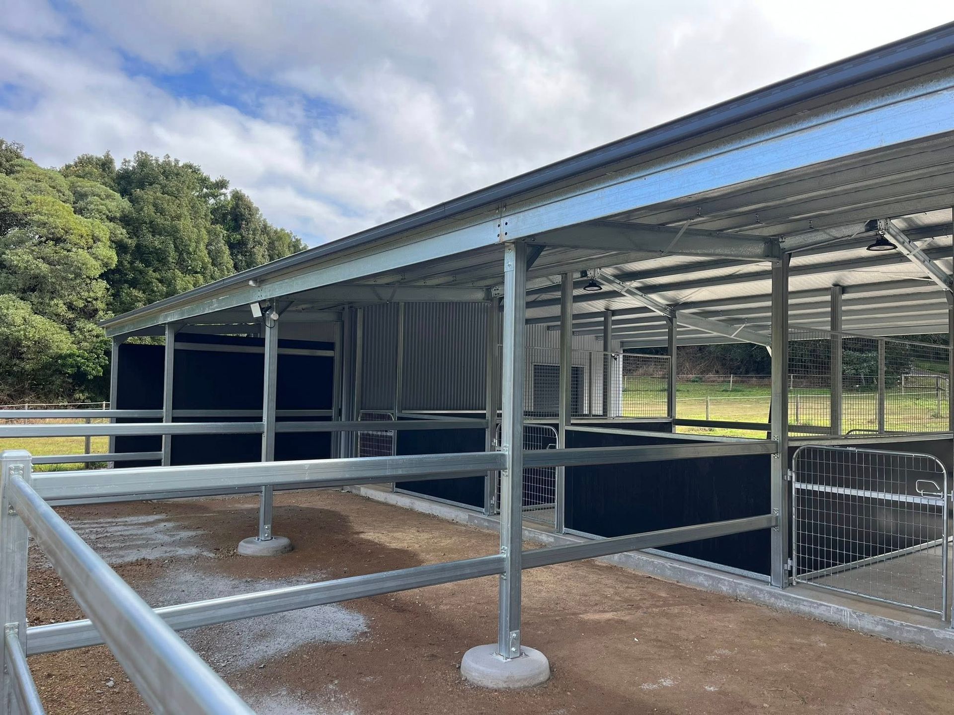 Metal horse stables with covered roof, set in a rural area, with gravel floor and fenced in areas. — Equine Stable Solutions In Diddillibah, QLD