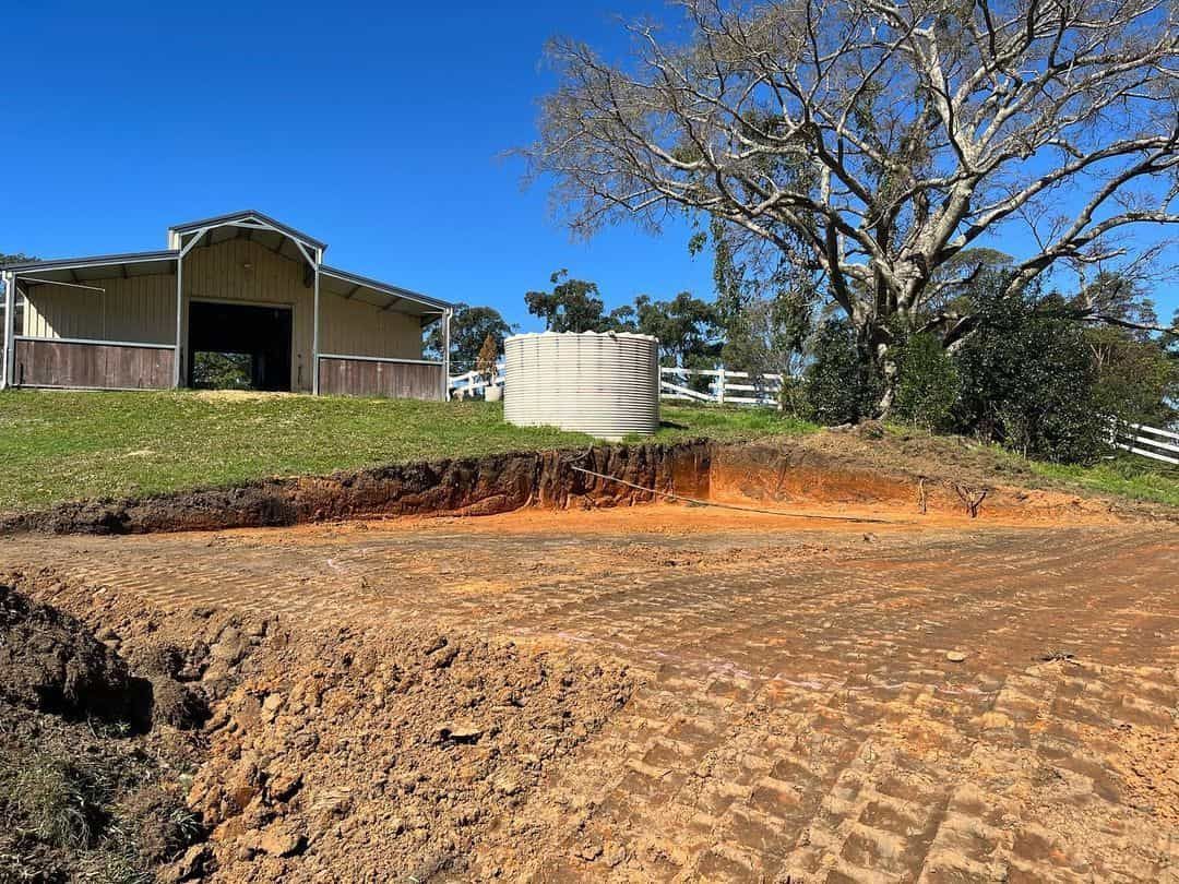 A Large Pile Of Dirt Is Sitting In Front Of A Horse Barn — Equine Stable Solutions In Gold Coast, QLD