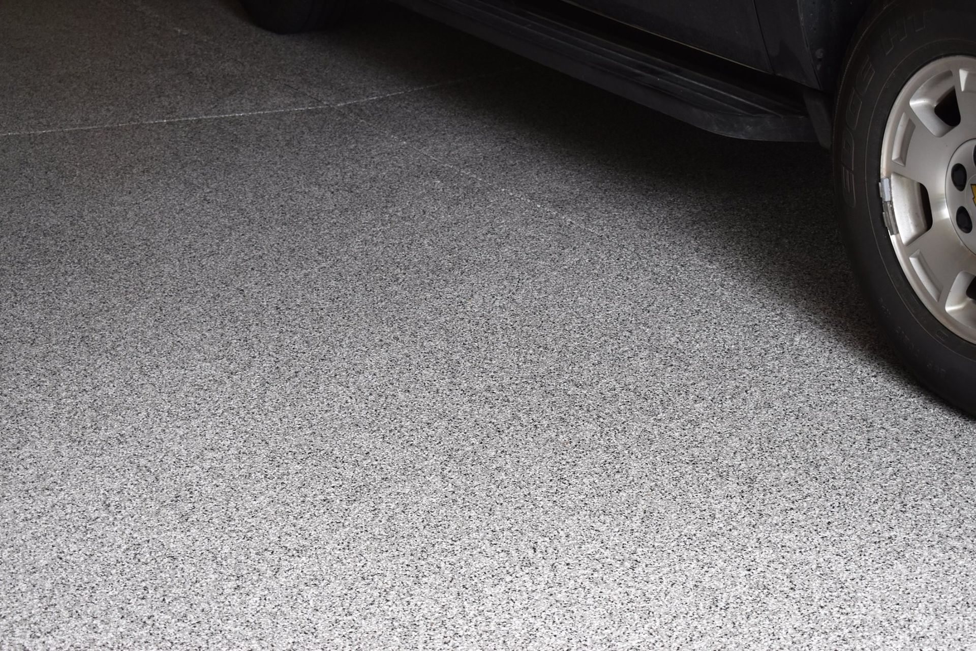 Car tire parked on a gray speckled floor