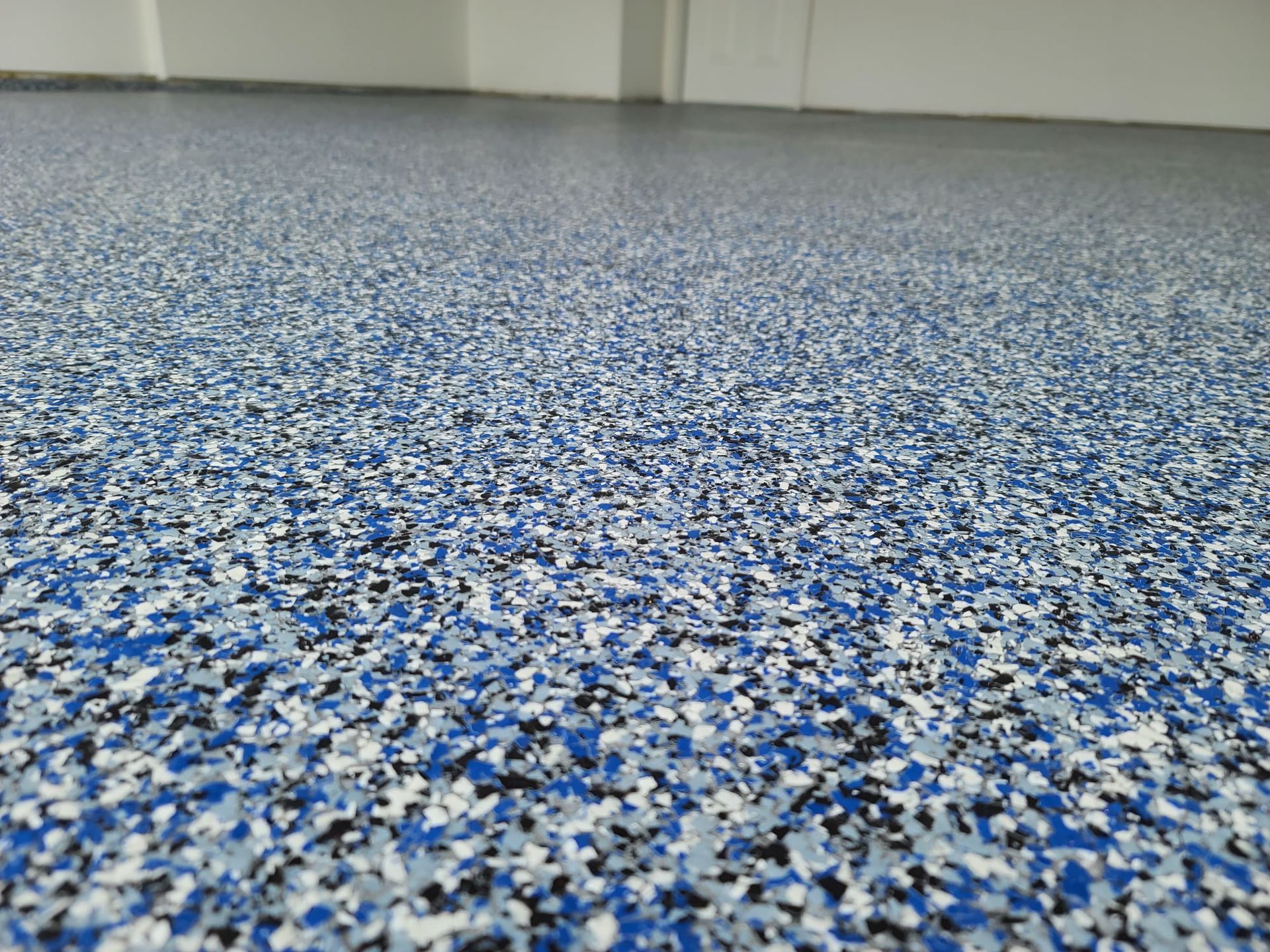 Blue-and-white speckled epoxy floor in a room with plain white walls