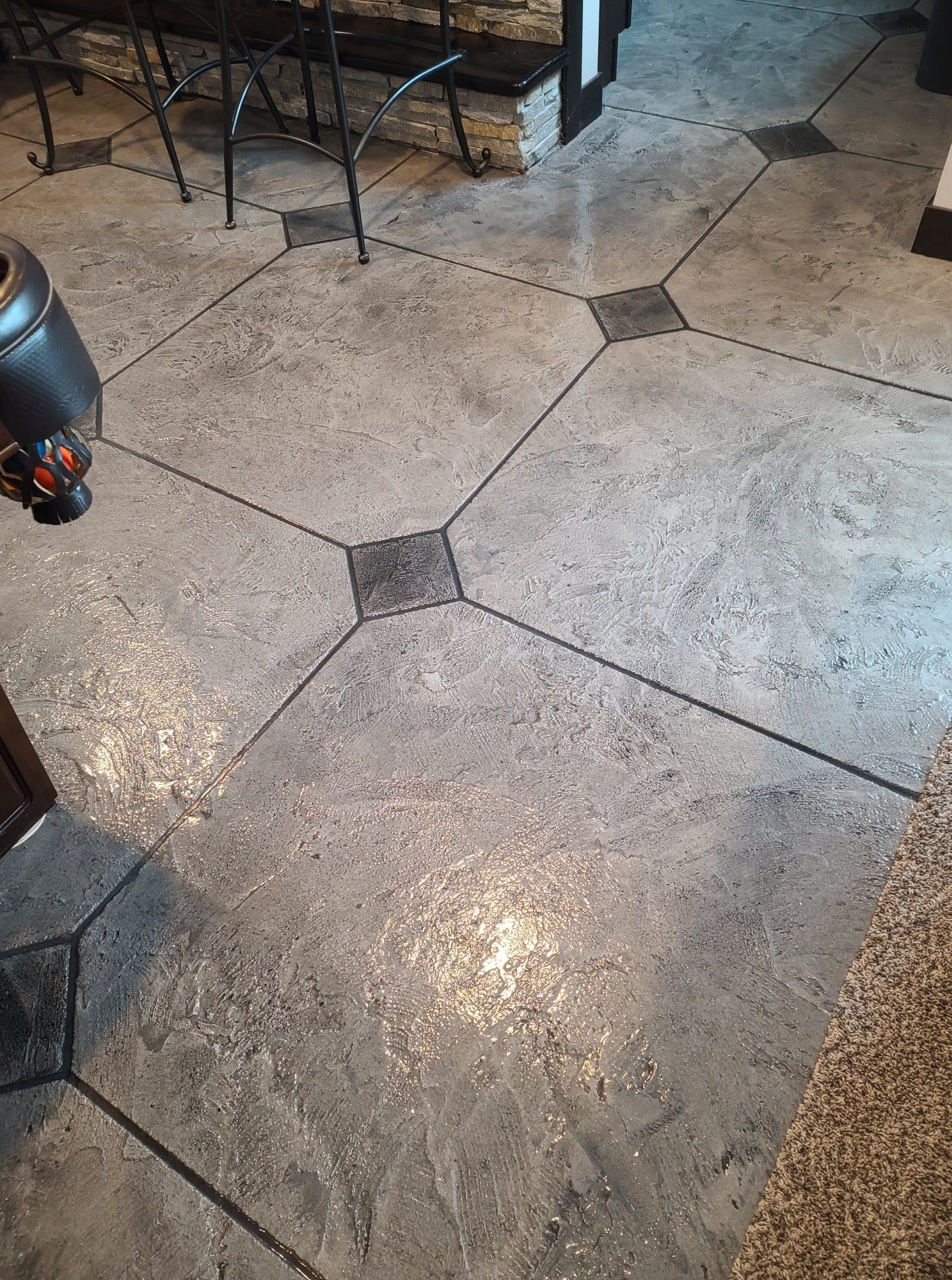 Stone floor with dark grout lines in a restaurant or patio setting, with a chair and heater partially visible.