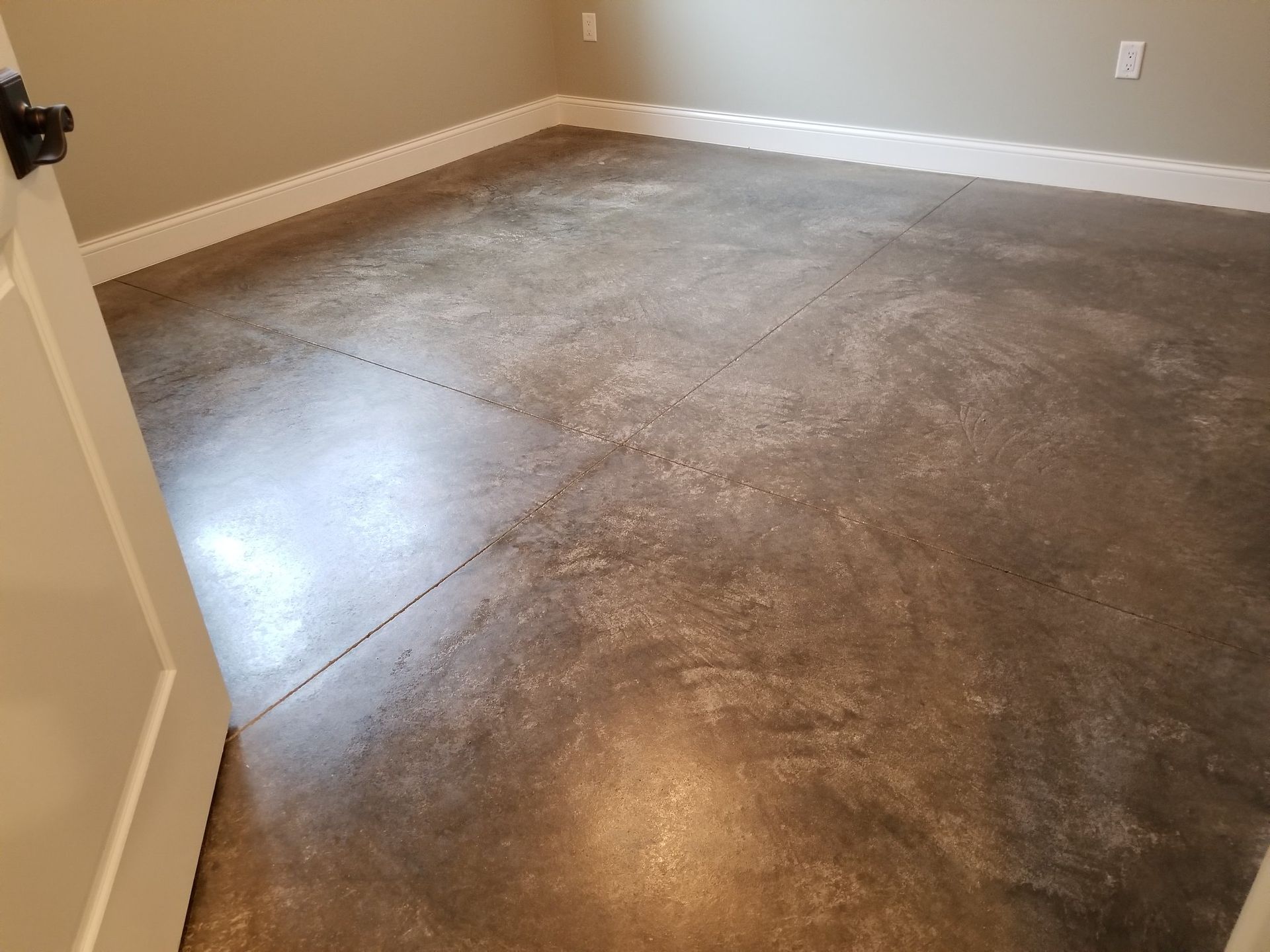 Empty room with gray concrete floor and beige walls, viewed from an open doorway