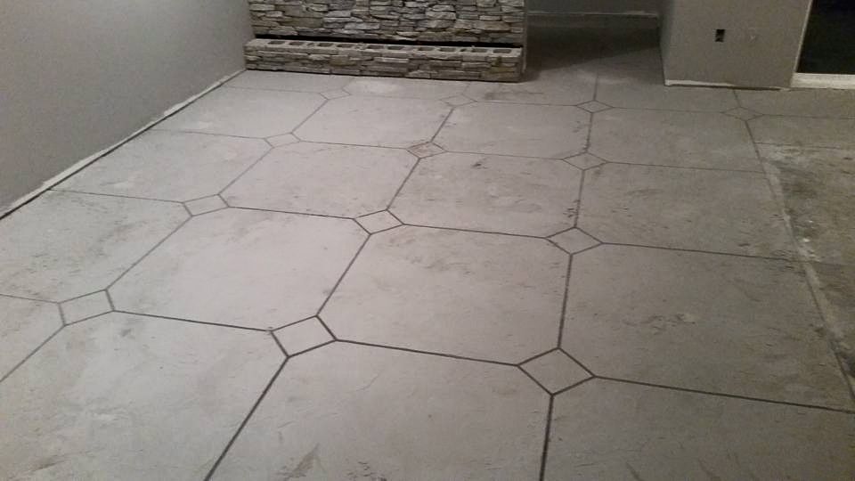 Light-colored stone patio with geometric tile pattern beside a brick wall and doorway