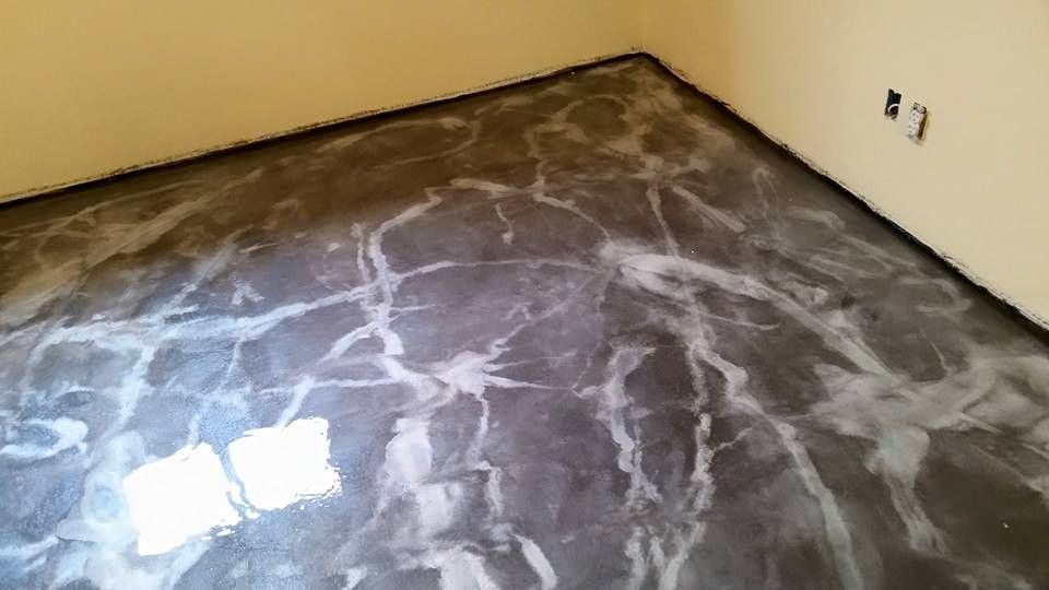 Empty room with dark marbled floor and cream walls, showing a glossy finish and wall outlets.
