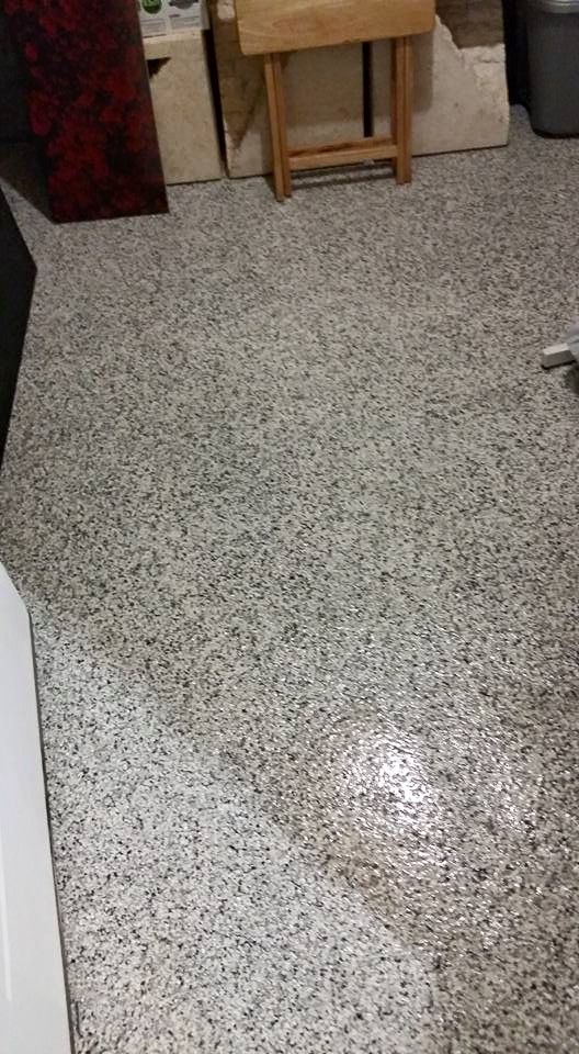 Speckled terrazzo floor with a small wooden table against a wall