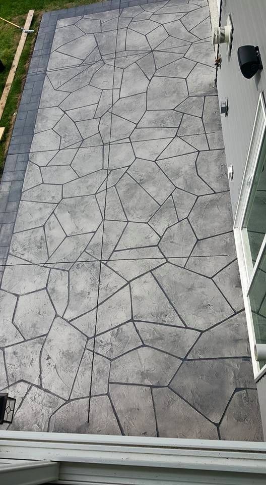 Textured gray stone patio beside a white wall and glass door.