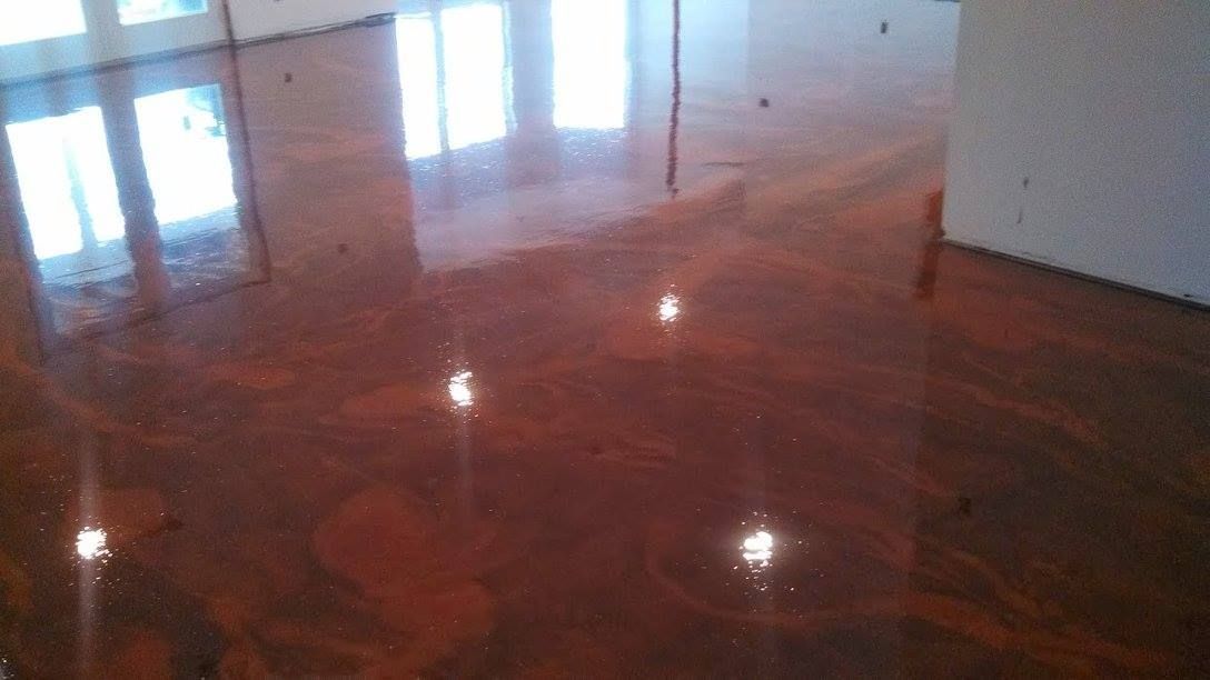 Polished wooden floor in a bright empty room with reflections of windows and ceiling lights.