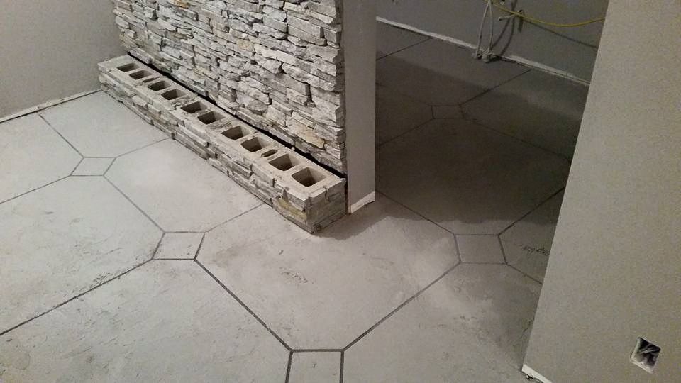 Partially renovated interior with hexagonal tile floor and exposed brick wall under construction