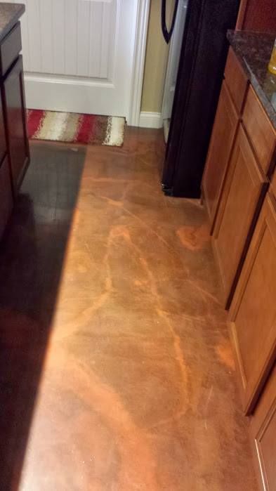 Narrow kitchen hallway with wood cabinets, vinyl floor, and a white door with a striped rug ahead.