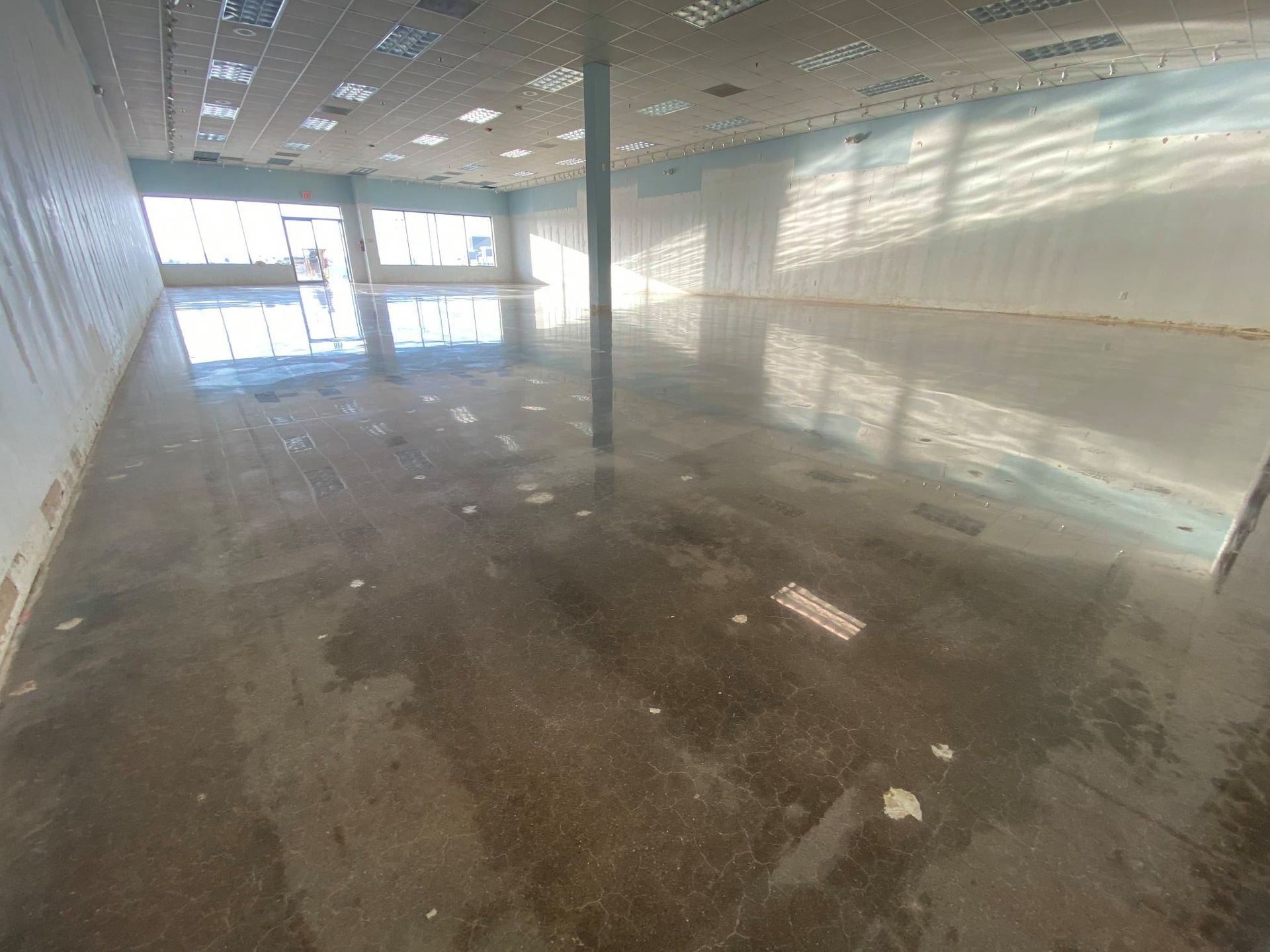 Empty flooded room with reflective water on the floor and sunlight through windows