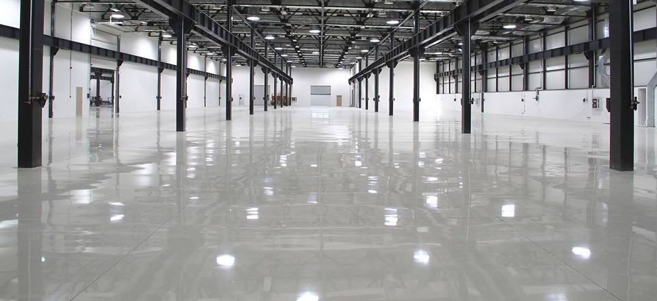 Empty industrial warehouse with polished concrete floor and exposed ceiling beams