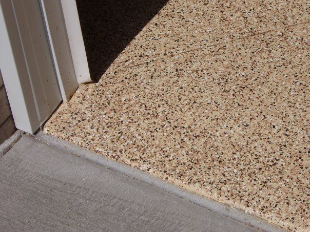 Close-up of a doorway threshold with gray flooring meeting a speckled beige carpet.