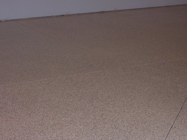 Close-up of a beige carpeted floor meeting a white wall and baseboard.