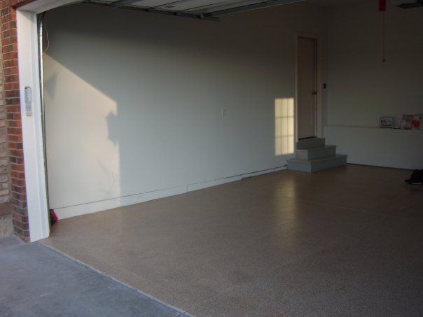 Empty garage with white walls, concrete floor, and small steps leading to a side door