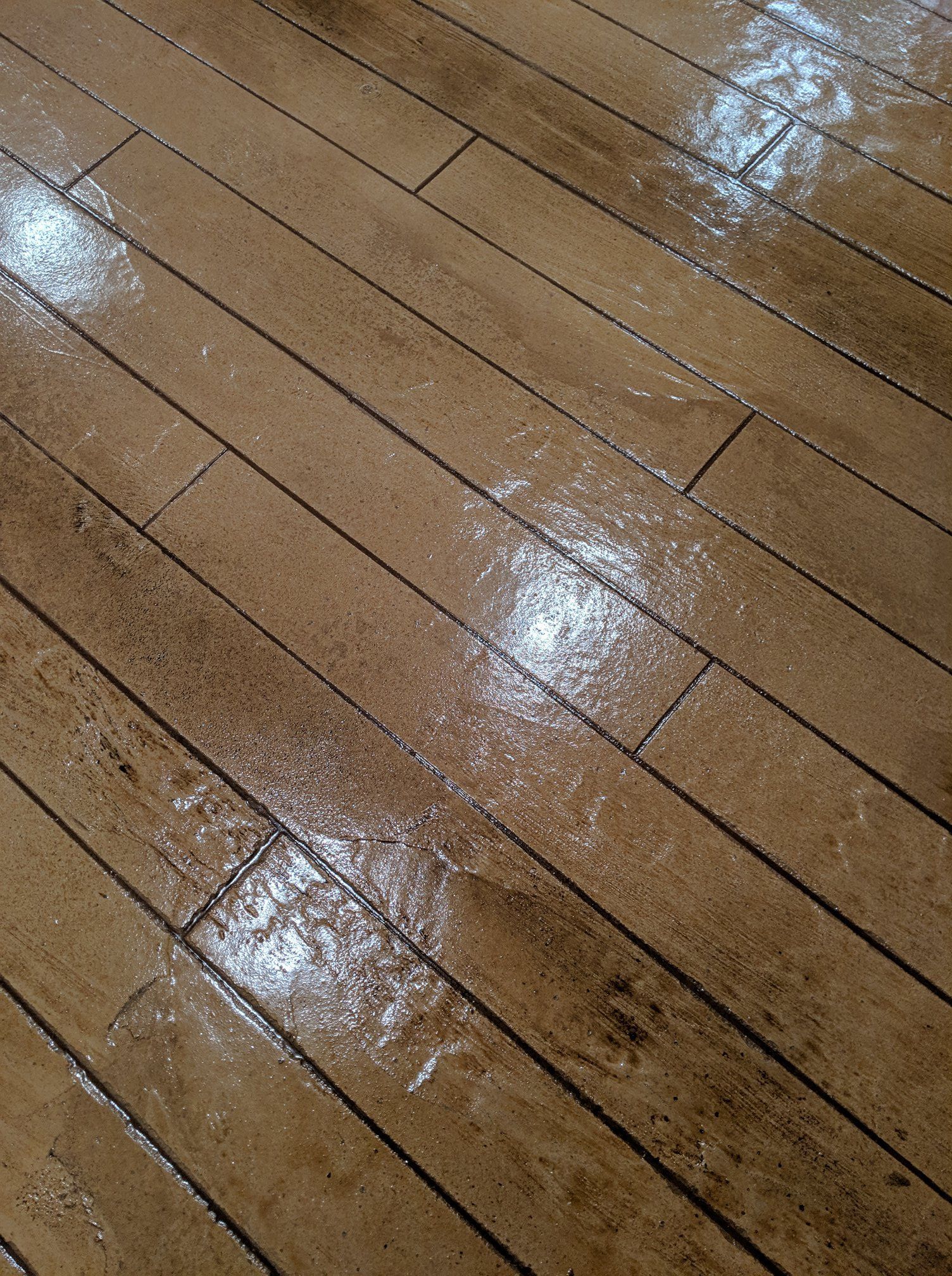 Wet wooden floor with reflections of light and a few dark marks