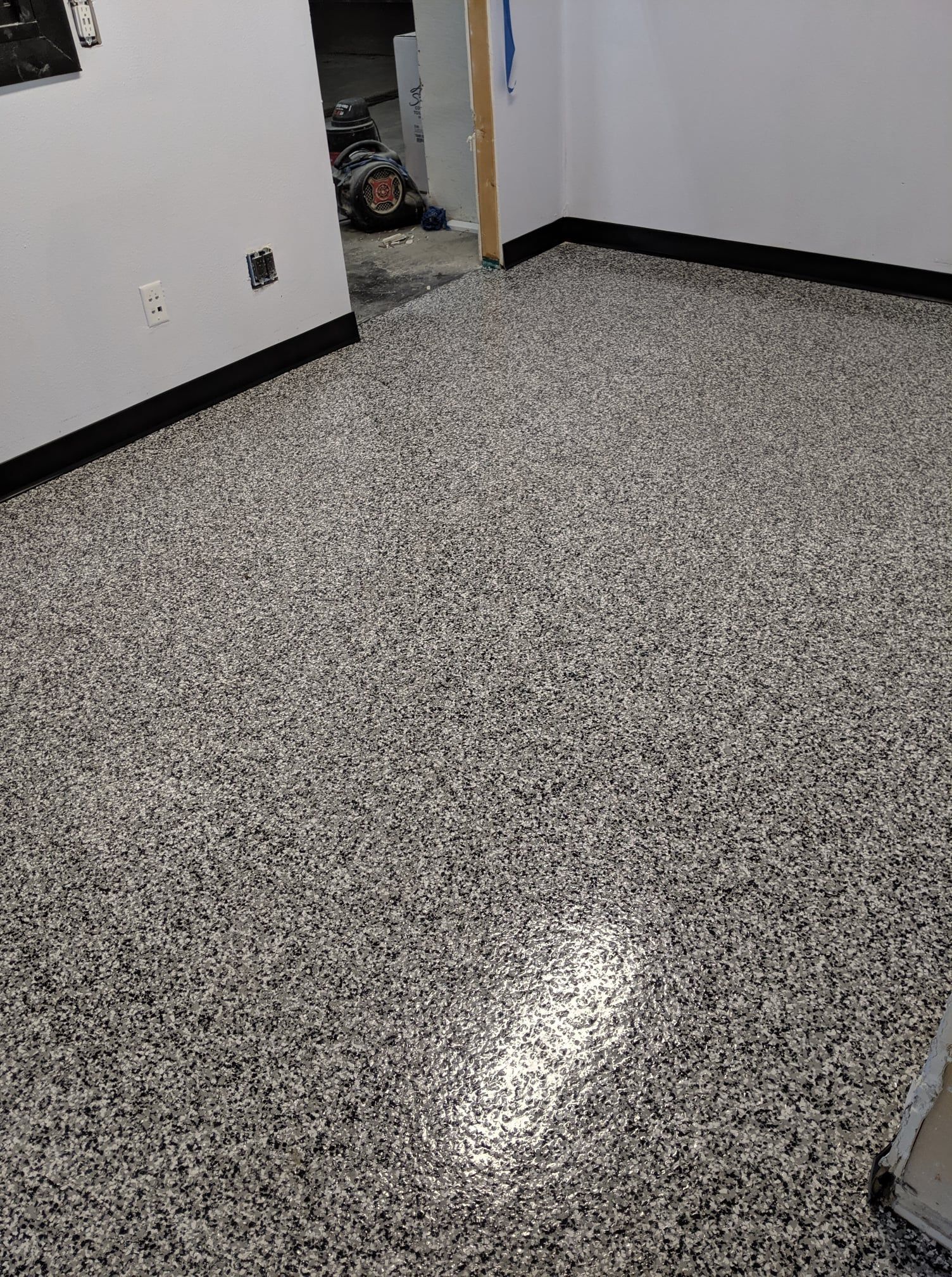 Empty room with speckled epoxy floor, white walls, and an open doorway.