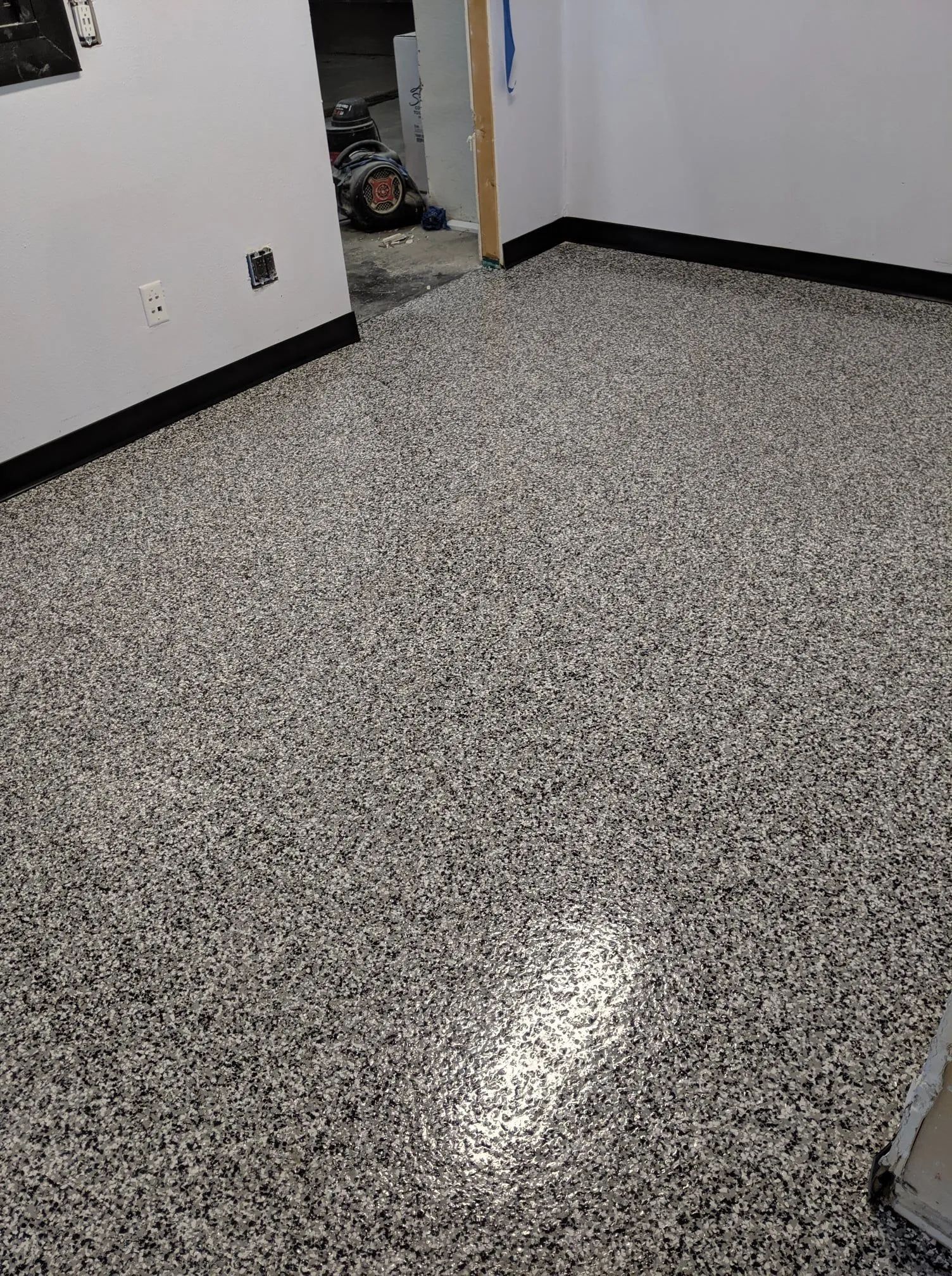 Empty room with speckled gray floor, white walls, and an open doorway.