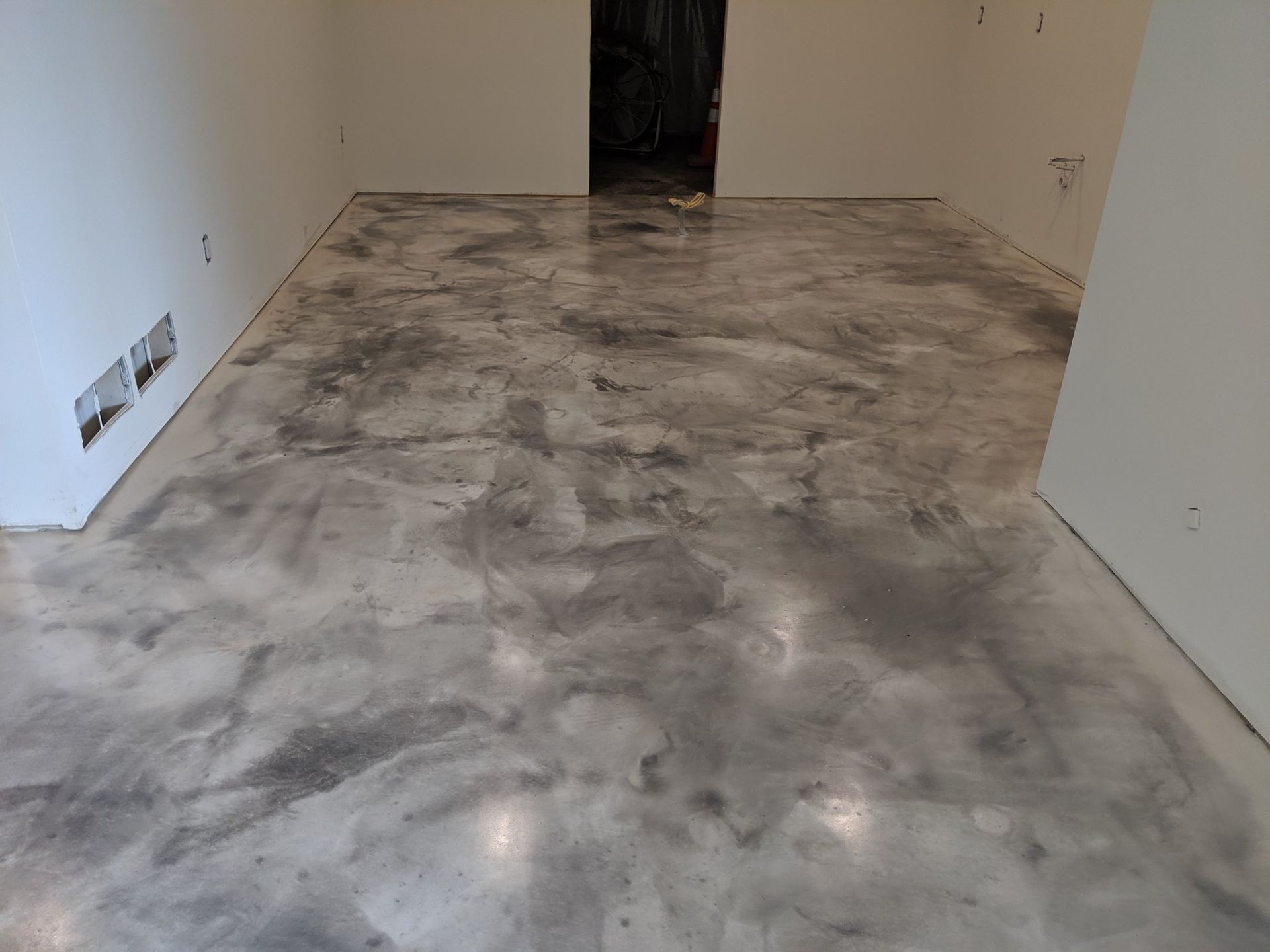 Empty room with unfinished gray concrete floor and white walls