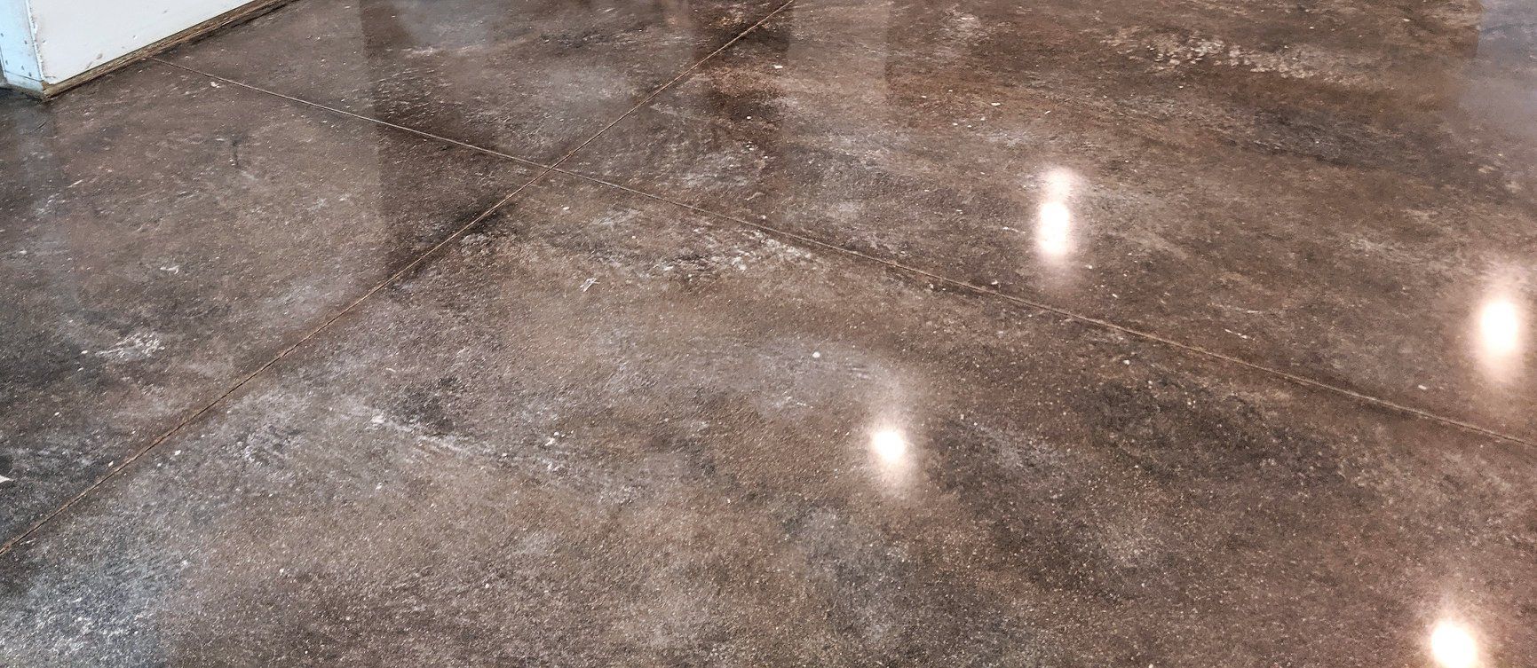 Shiny brown polished floor with reflections of overhead lights