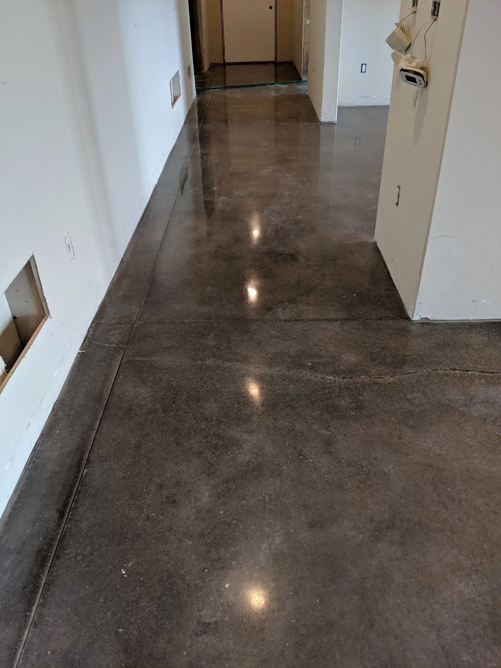 Empty hallway with polished concrete floor and white walls, reflecting ceiling lights