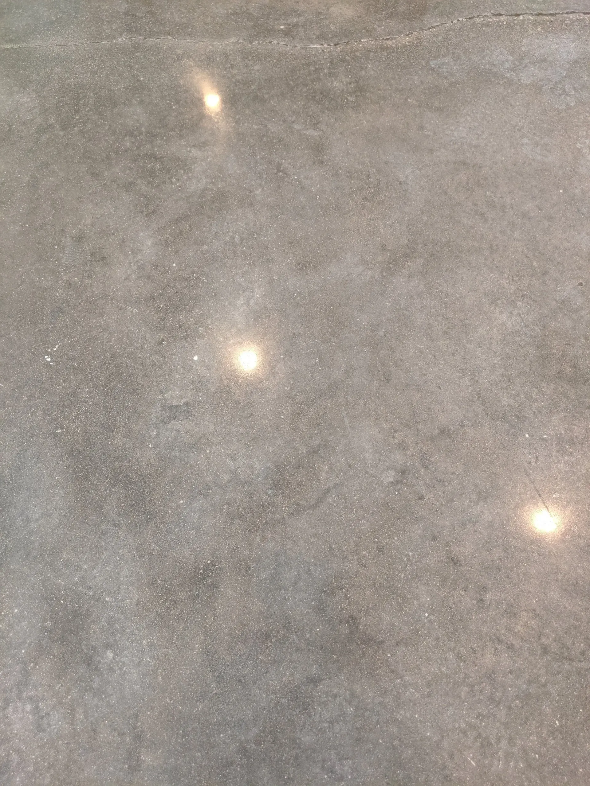 Gray speckled surface with three small bright reflections or lights