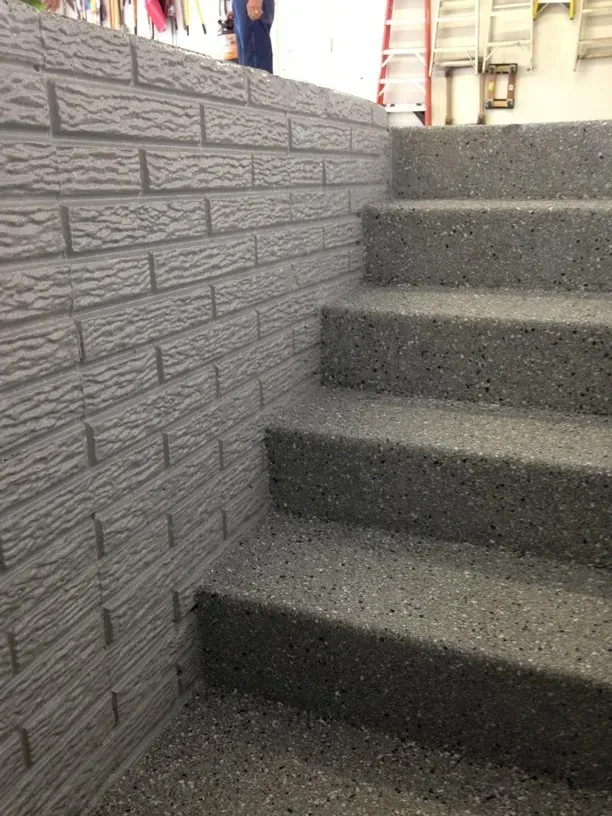 Carpeted indoor staircase beside a gray brick-pattern wall