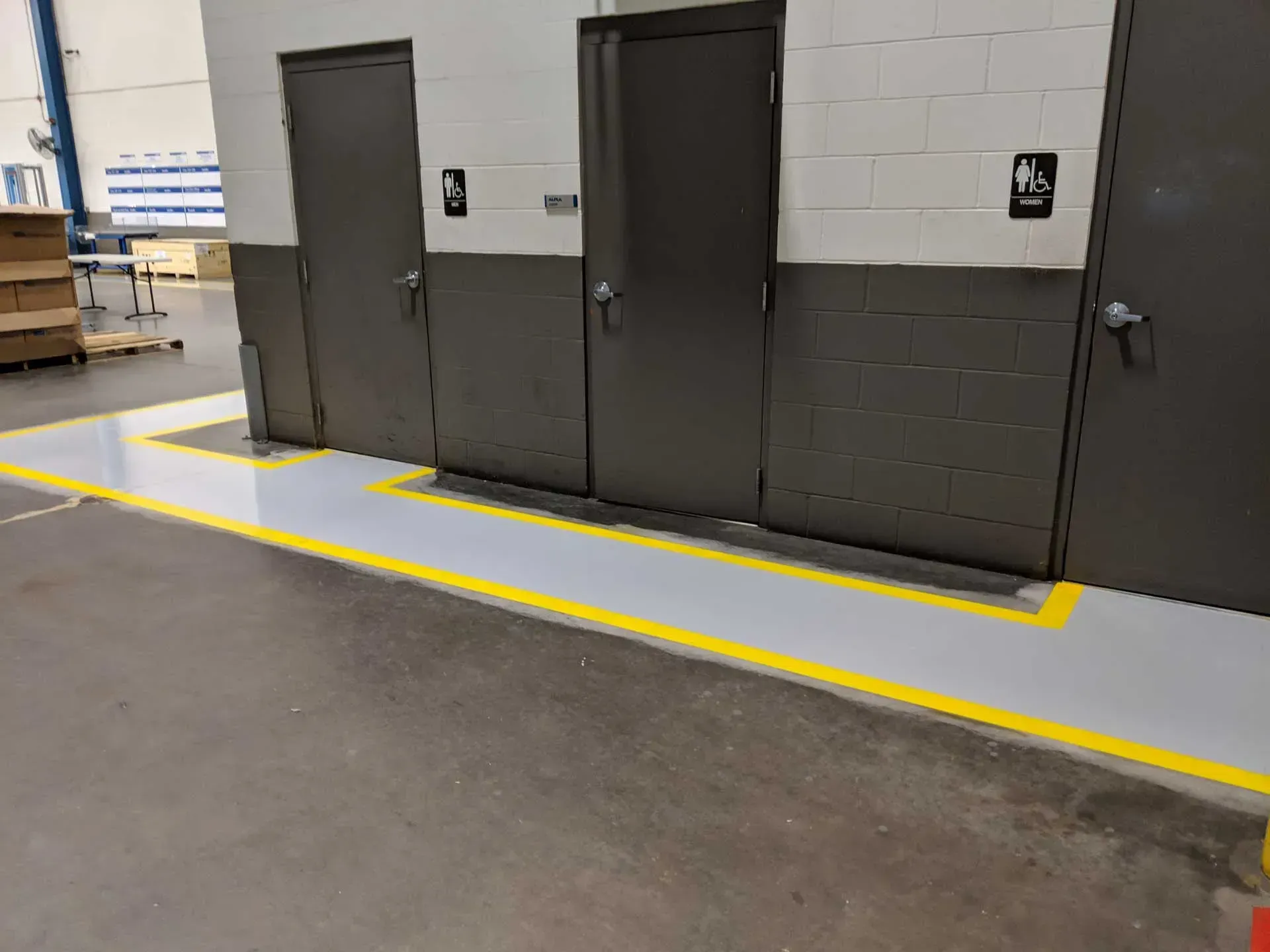 Yellow-bordered loading area beside gray industrial doors in a warehouse corridor.