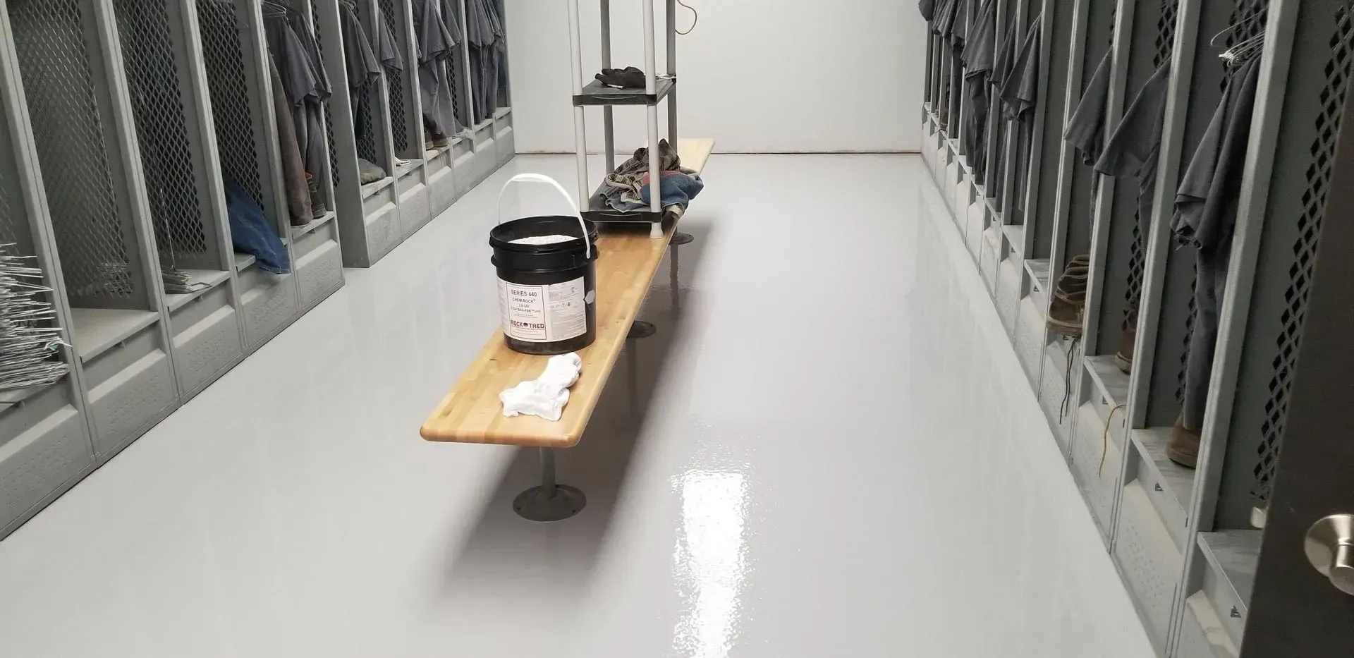 A hallway with metal railings and a wooden bench holding a white container on the floor.