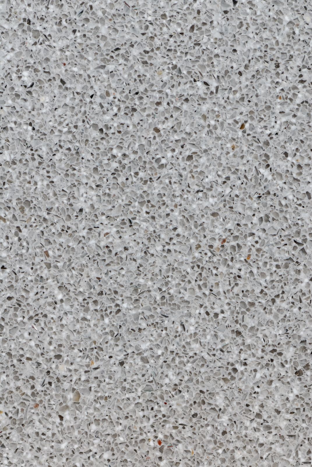 Speckled light gray textured surface with small dark and tan flecks