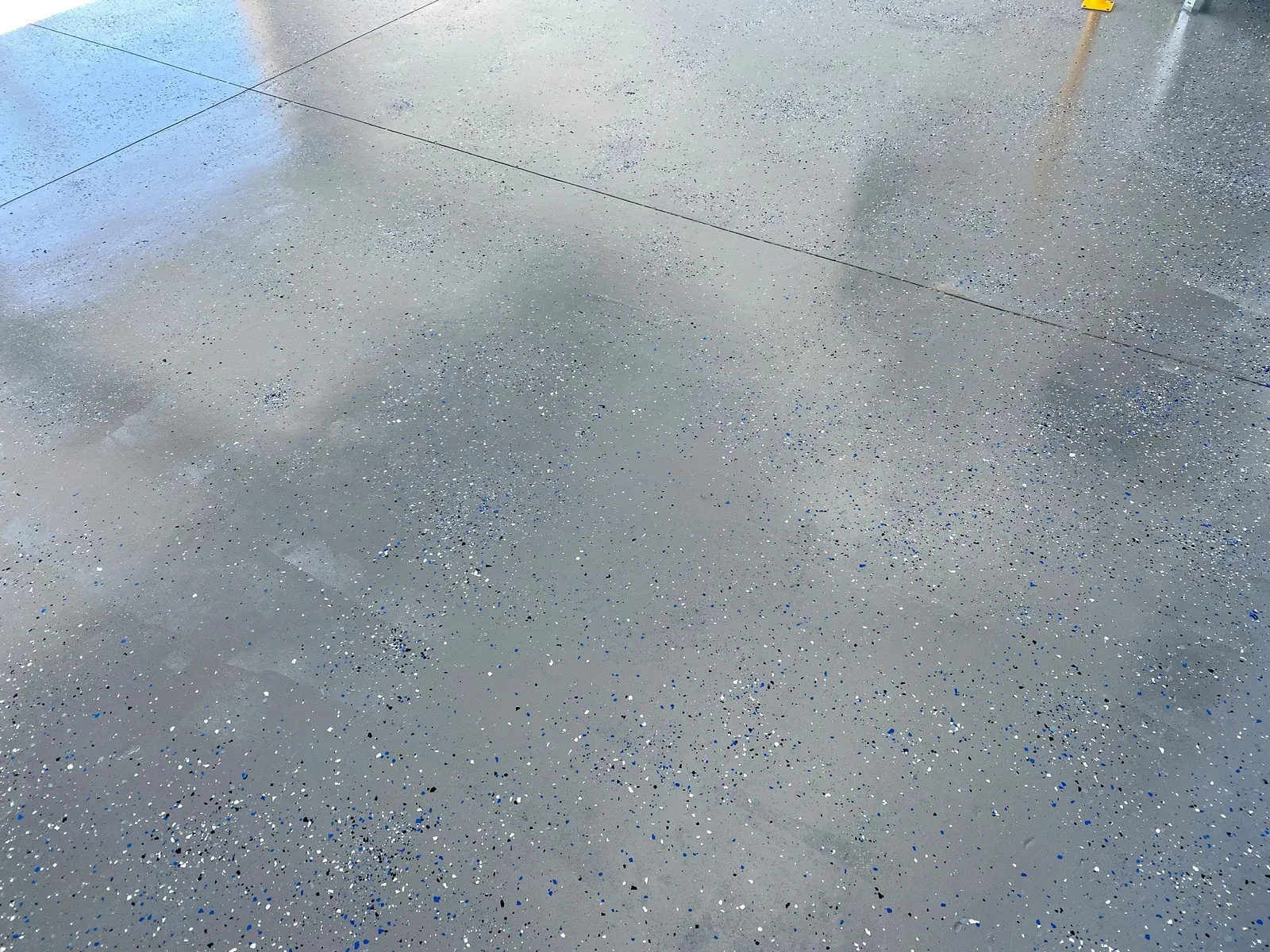 Gray concrete floor with scattered dark specks and soft reflections of light