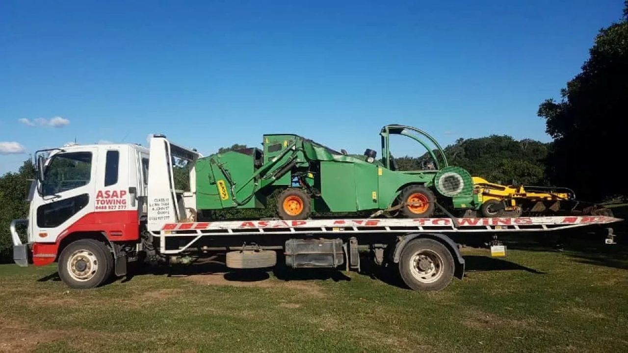 A Green Farm Machine is Loaded on a Flatbed Truck — ASAP Towing Pty Ltd In Tin Can Bay, QLD