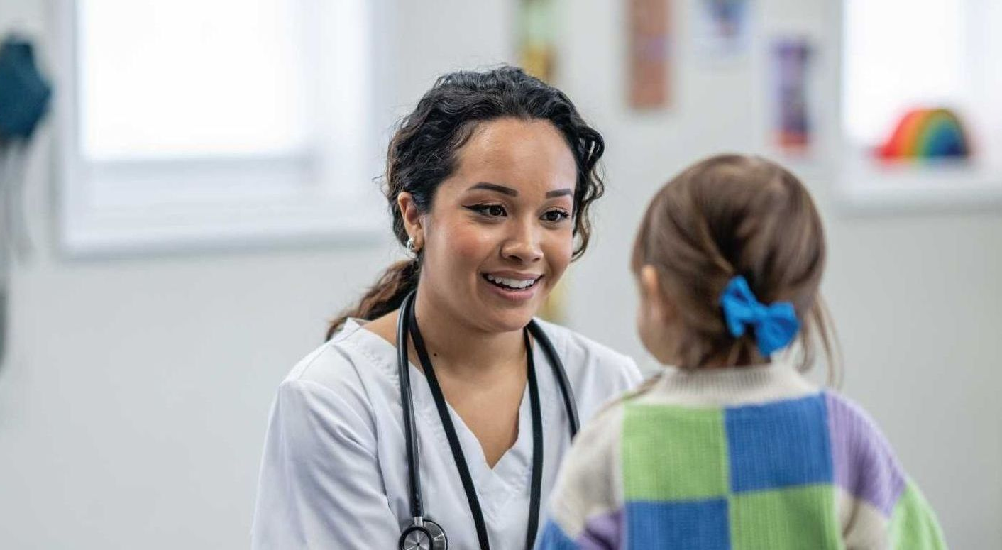 Doctor smiling and talking with a child in a bright clinic room